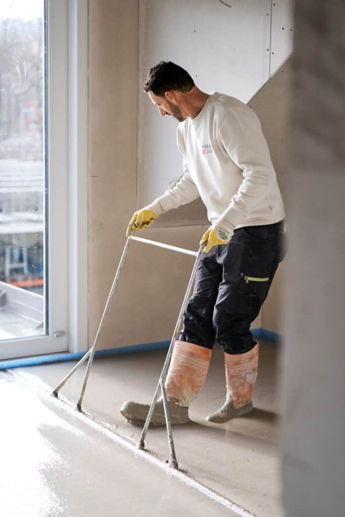 Ein Mitarbeiter von Feld Fußbodensysteme bringt Estrich fachgerecht ein.